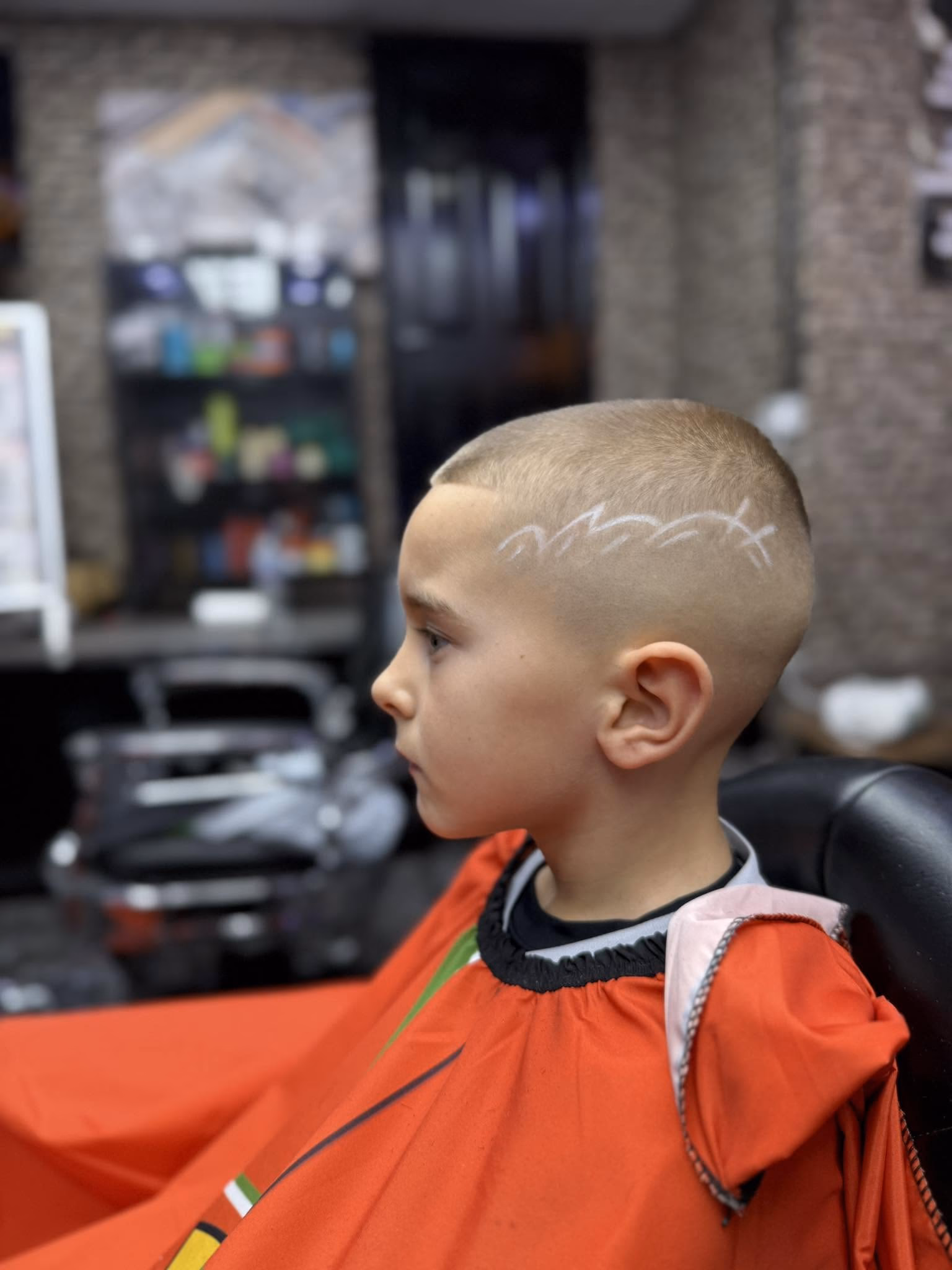 Short all-over buzz cut with a freehand design shaved along the side, side profile