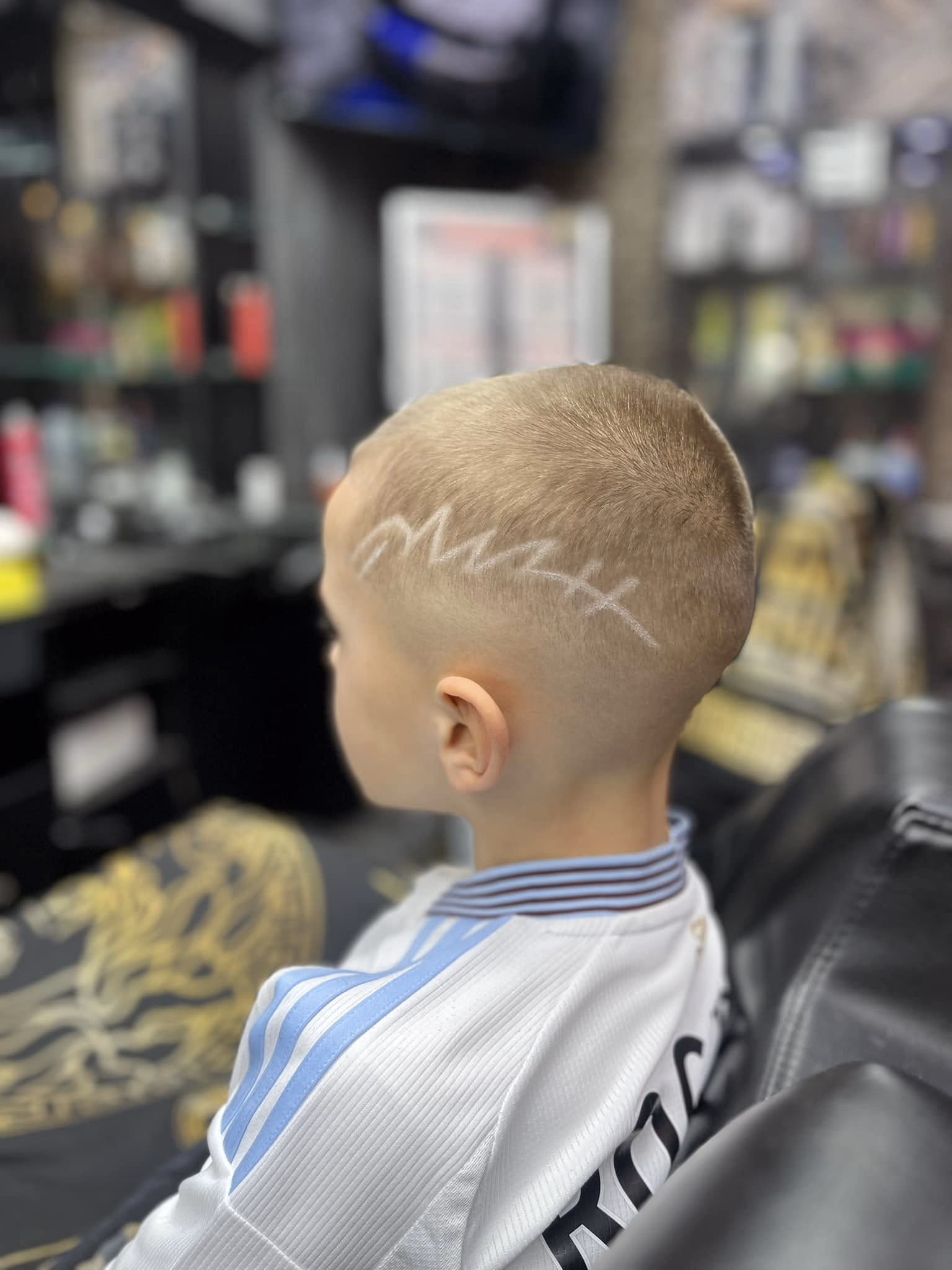 Short buzz cut with a name shaved into the side in freehand script, side view