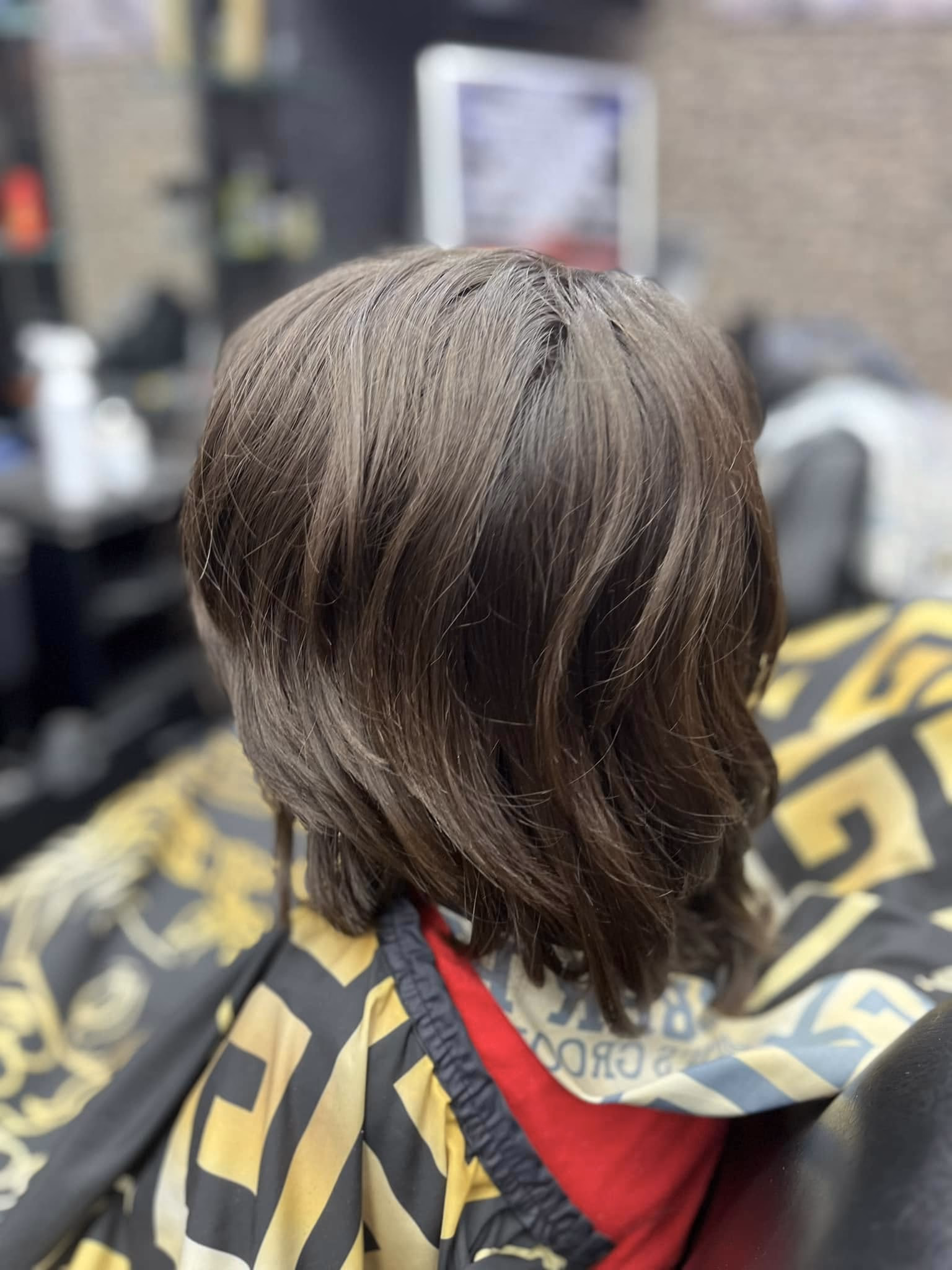 Collar-length layered cut with soft movement through the ends, no fade, seen from behind