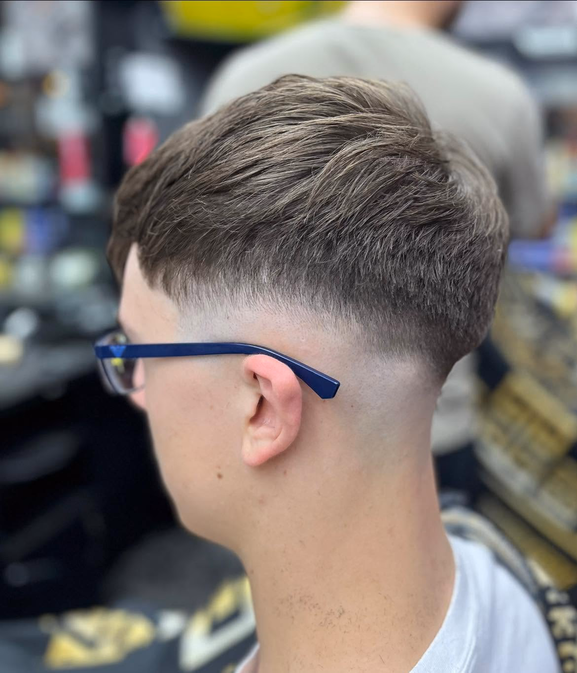 Mid fade with a short textured top pushed forward into a soft fringe, side profile