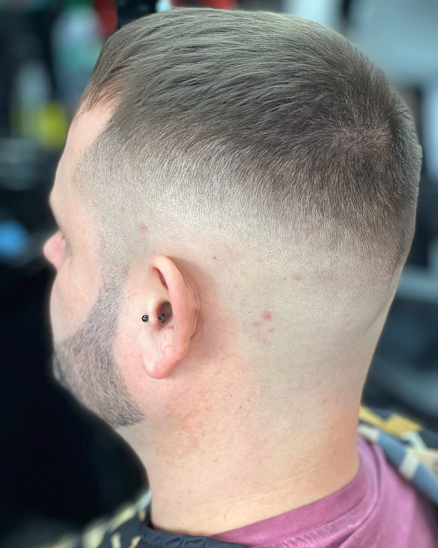 Short back and sides with a soft taper above the ear and a cropped top, side profile