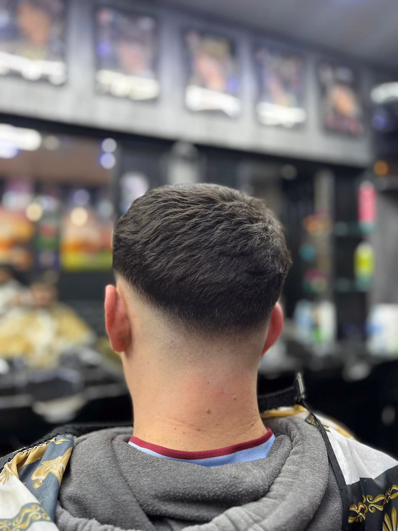 Natural length left on top over a clean low taper fade around the ears and nape, seen from directly behind