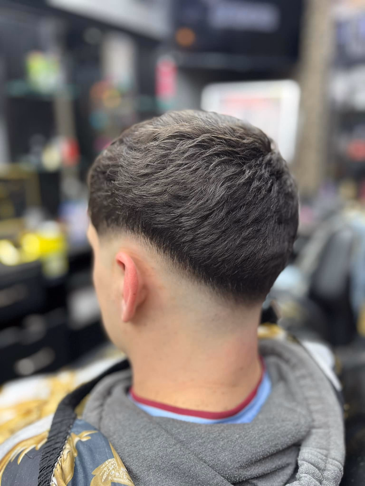Textured crop with movement through the top over a low taper fade, rear three-quarter view