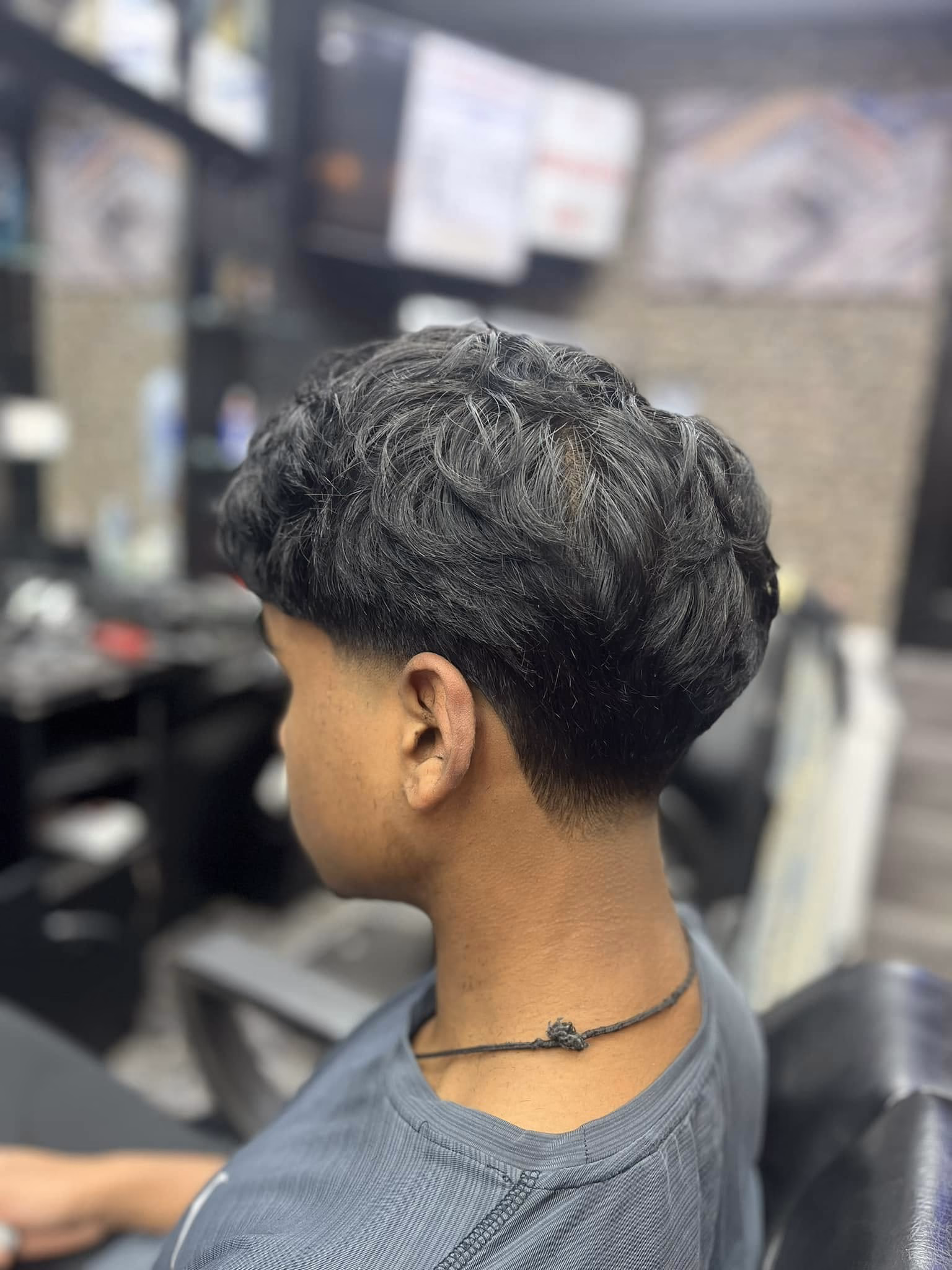 Wavy hair cut into a rounded crop with a tapered neckline and natural texture left through the top, side view